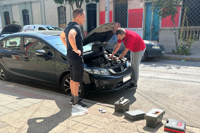 Capô de carro aberto fazendo manutenção e trocando a bateria antes de viajar. Como planejar uma roadtrip